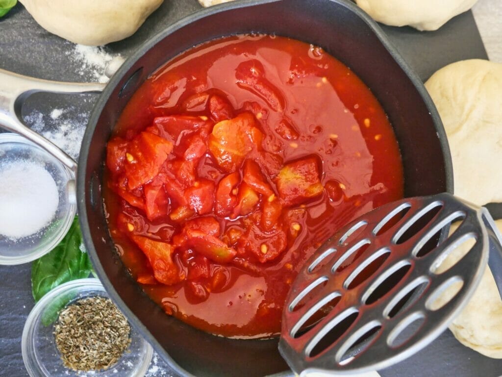 mashing tomatoes in pizza sauce
