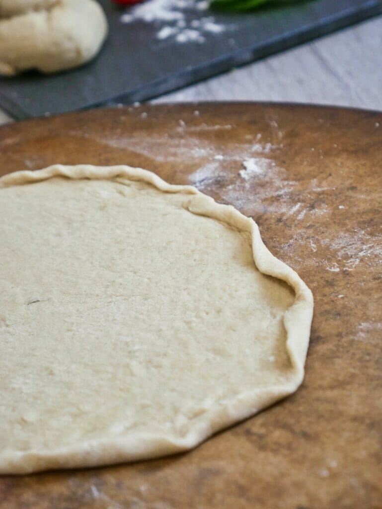 uncooked pizza crust with sides rolled up