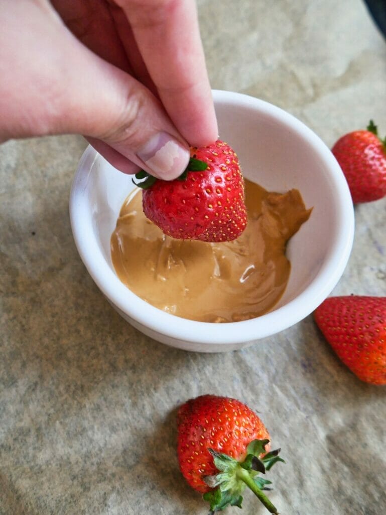 dipping strawberry in peanut butter