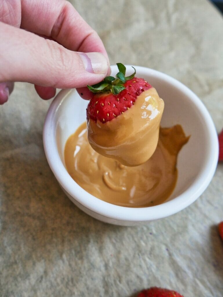 dipping strawberry in peanut butter