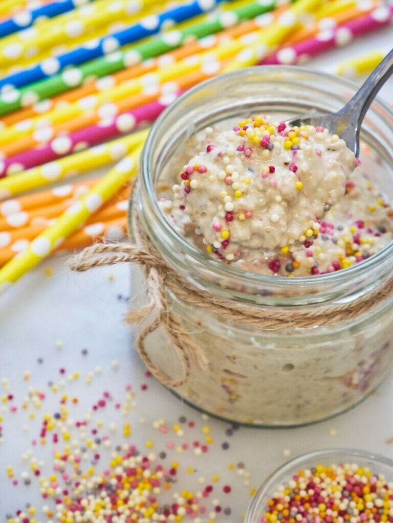 spoon with birthday cake overnight oats in a mason jar