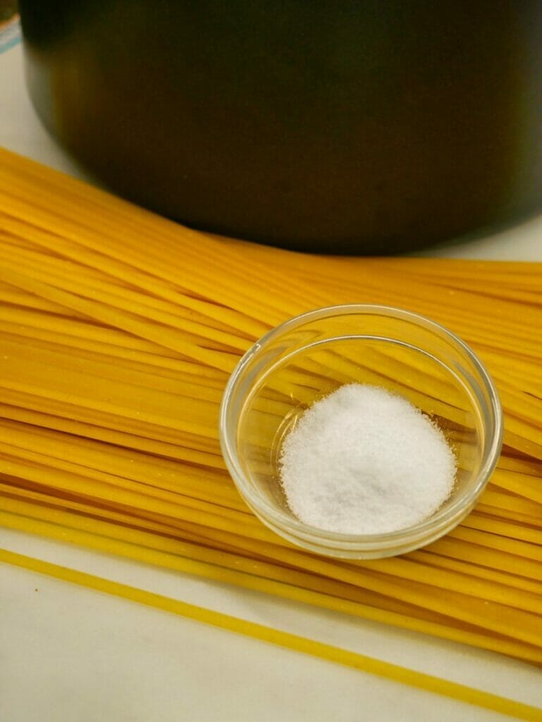 spaghetti and salt next to a pot