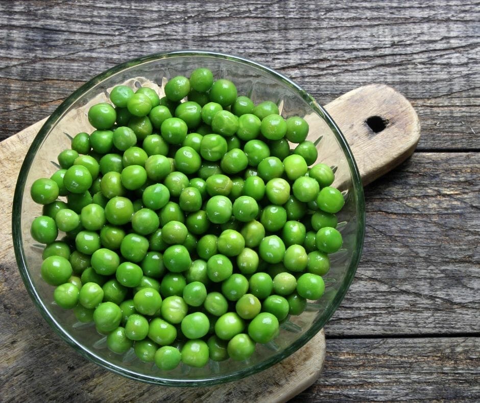 Green peas in a bowl on a wooden table 
