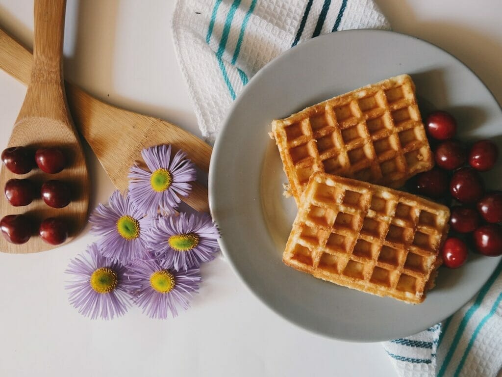 Waffles on a plate with flowers next to them 